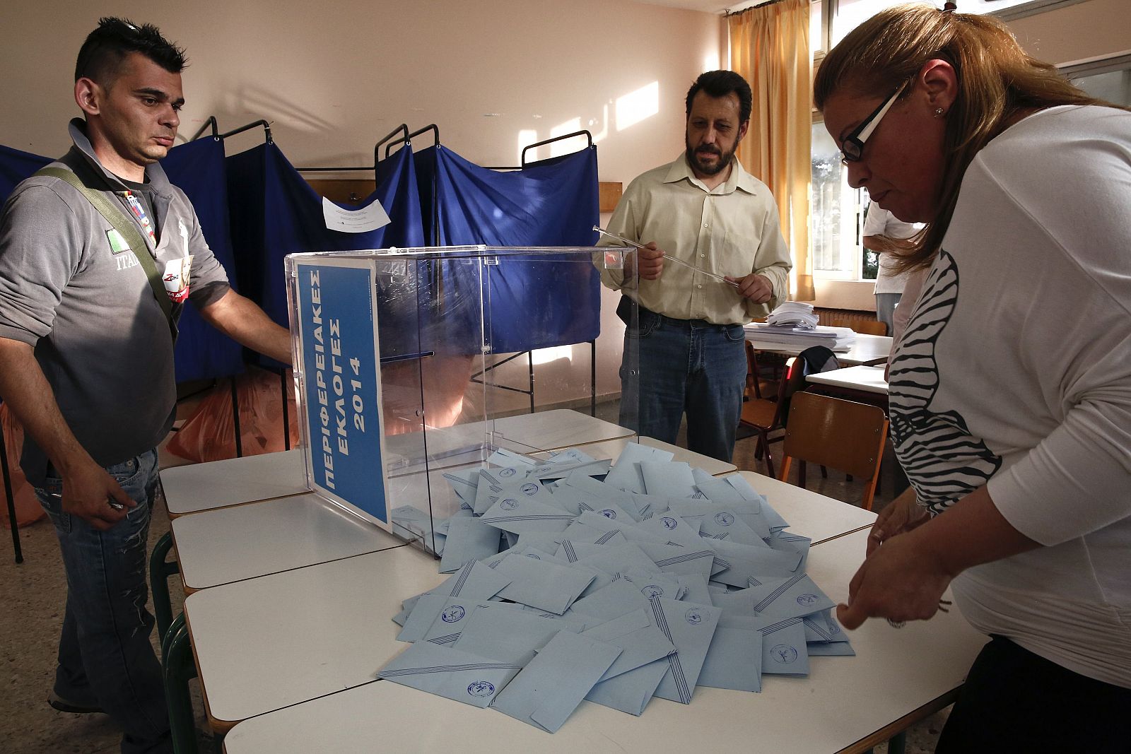 Miembros de la comisión electoral y un representante judicial vacían una urna tras la jornada de votación en las elecciones locales y municipales en Grecia.