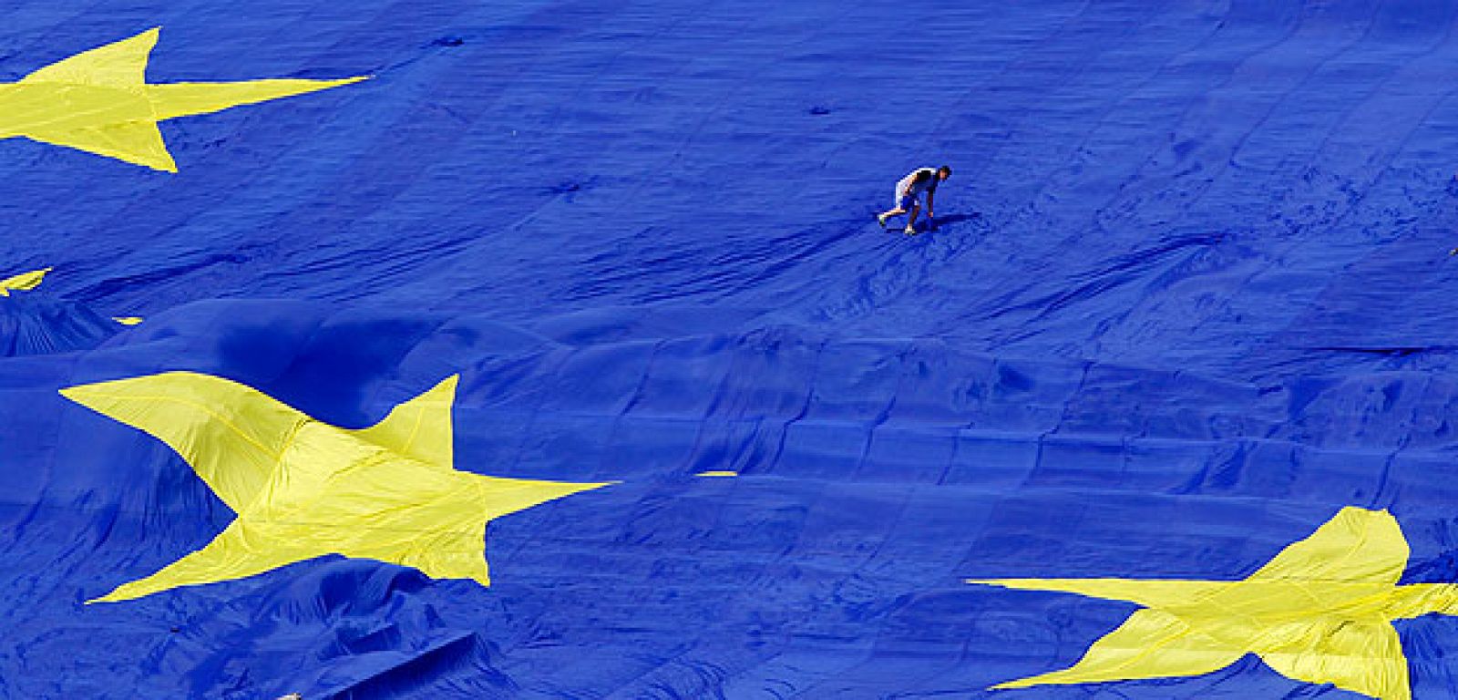Un hombre camina sobre una bandera gigante de la UE