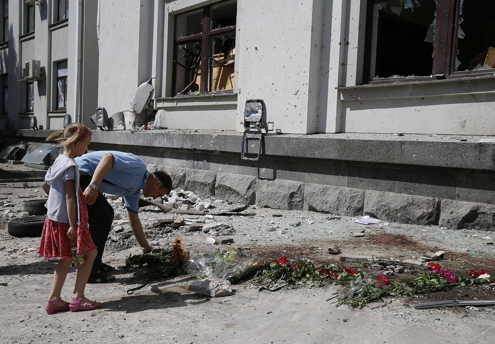 Un hombre deposita flores frente al edificio administrativo de Lugansk, Ucrania, donde se produjo una explosión en la que murieron dos personas