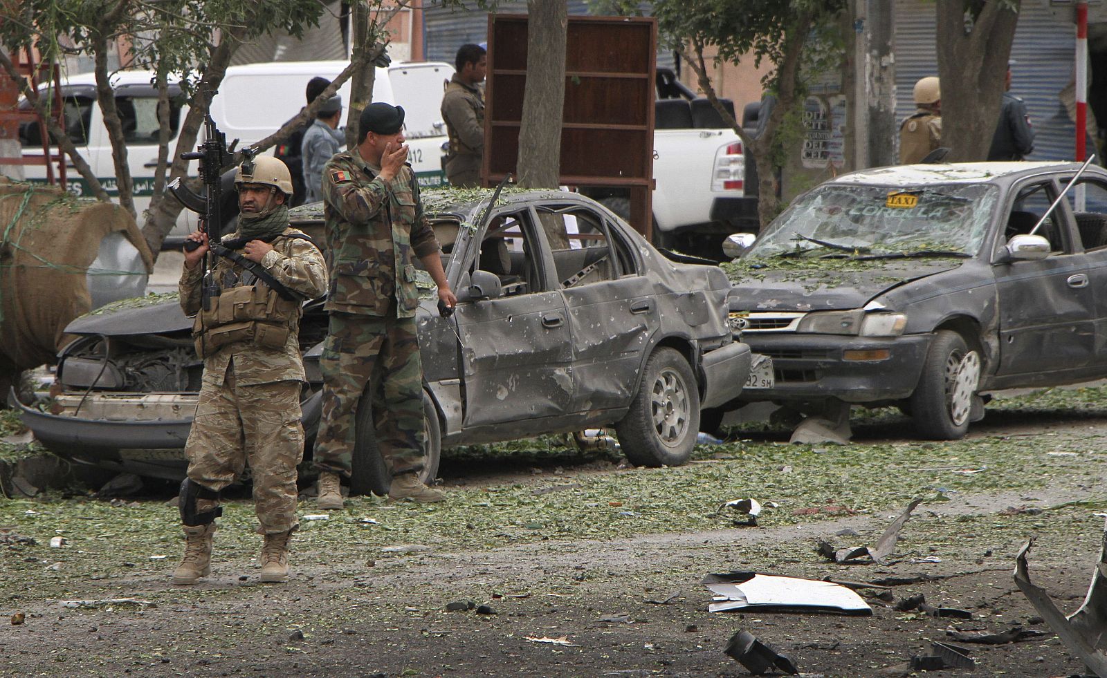 Oficiales de seguridad afganos inspeccionan el escenario de un atentado suicida perpetrado contra el convoy en el que viajaba Abdulá Abdulá, en Kabul (Afganistán).