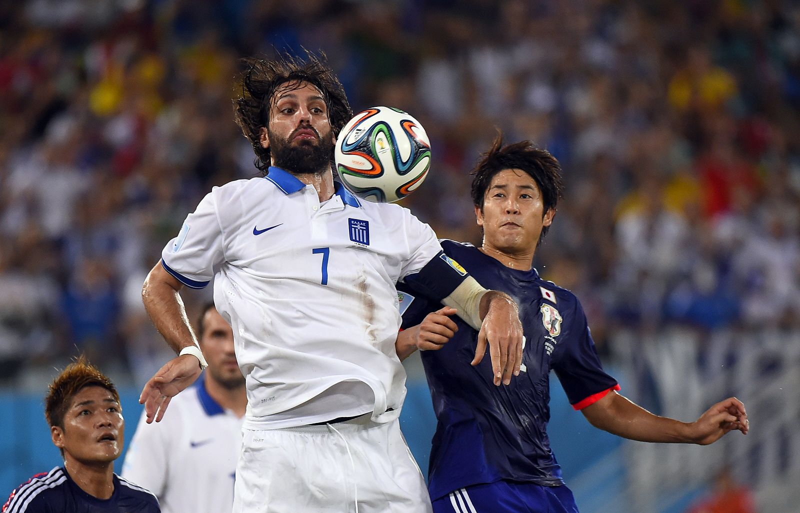 El delantero griego Georgios Samaras (izqueirda) y el defensor japonés Atsuto Uchida (derecha)  luchan por el control del balón