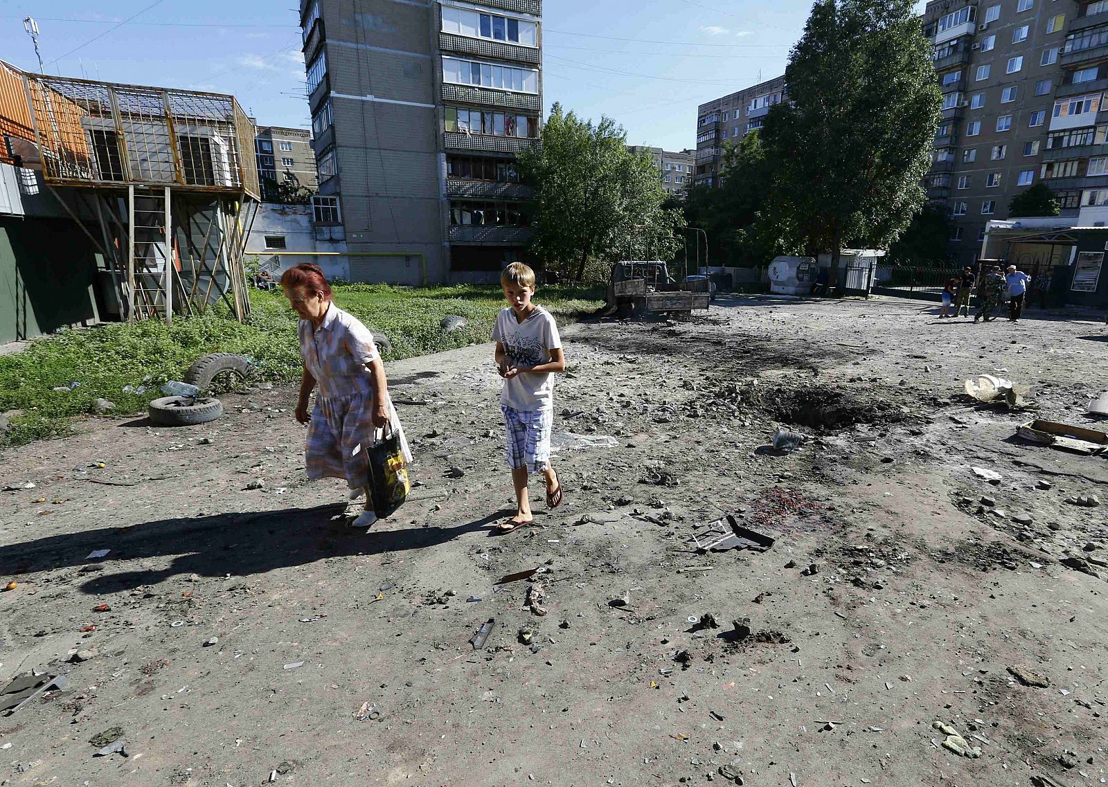 Residentes de Slaviansk, en el este de Ucrania, pasan junto a un cráter causado por la artillería