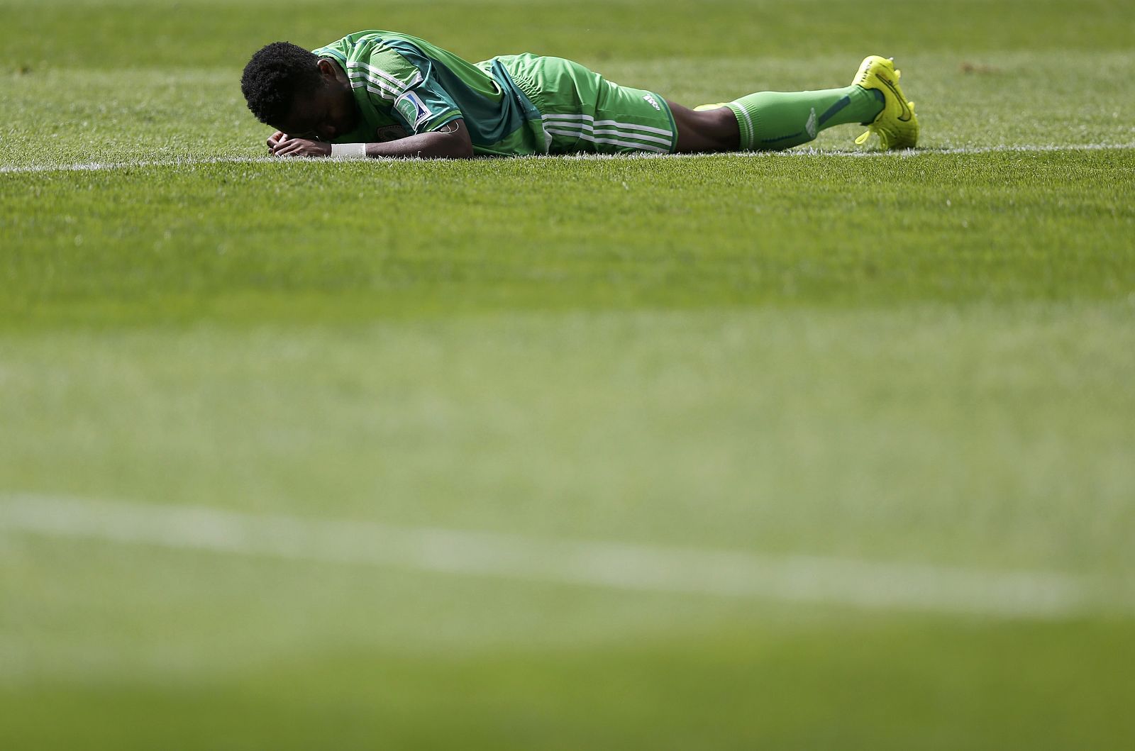 Nigeria's Ogenyi Onazi lies on the pitch after a challenge during their 2014 World Cup round of 16 game against France at the Brasilia national stadium in Brasilia