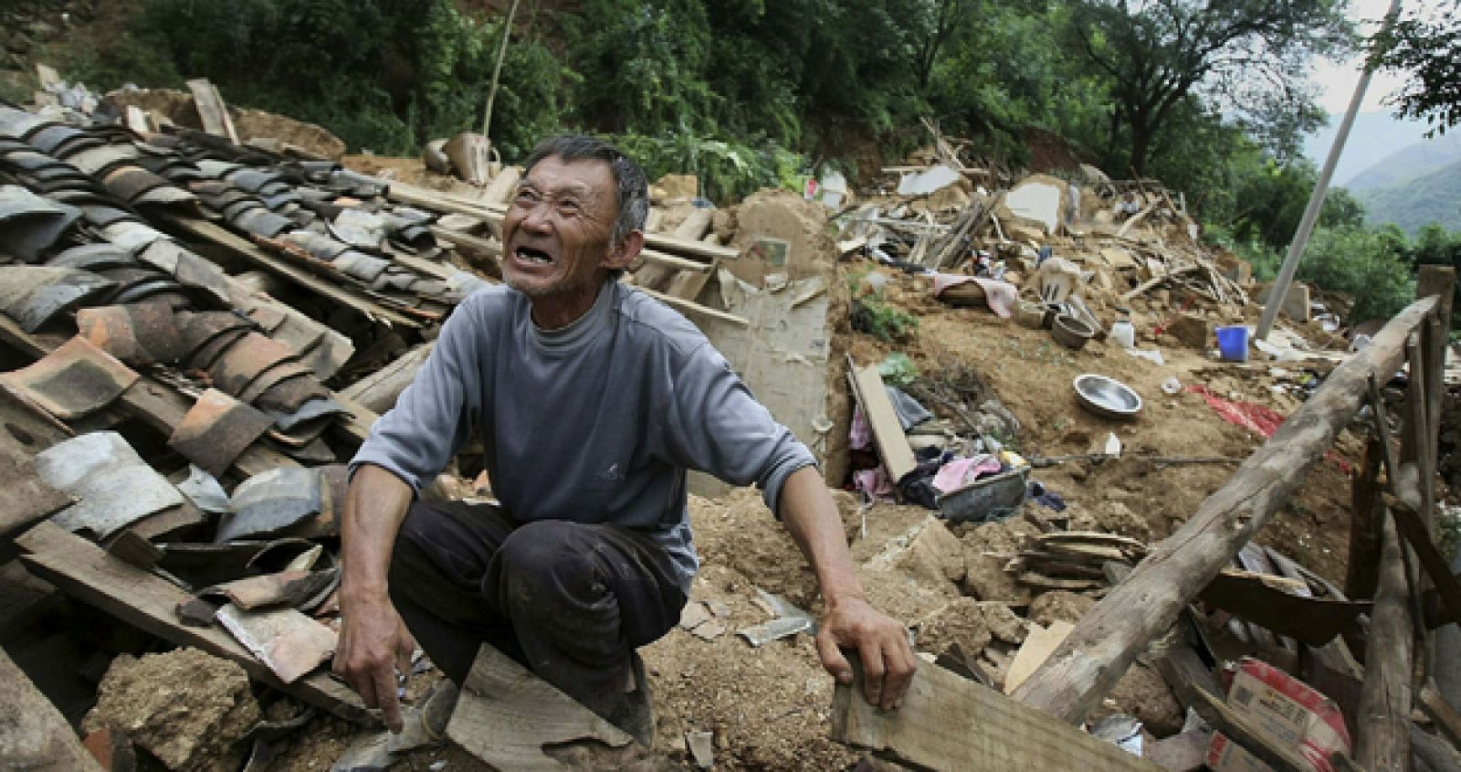 Un hombre que ha perdido a sus hijos llora sobre las ruinas de su casa en la ciudad de Longtoushan, donde se situó el epicentro del terremoto que sacudió el condado de Ludian el pasado domingo