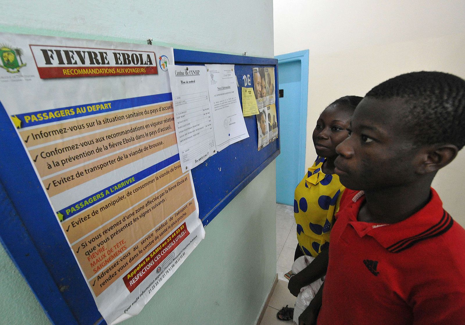 Varias personas leen un cartel que advierte sobre el virus del Ébola en Nigeria