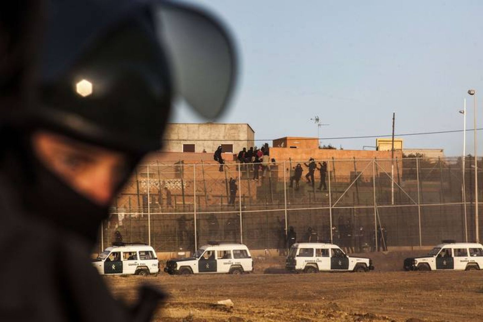 Agentes de la Guardia Civil escalan la valla fronteriza de Melilla para evitar el asalto de los inmigrantes subsaharianos