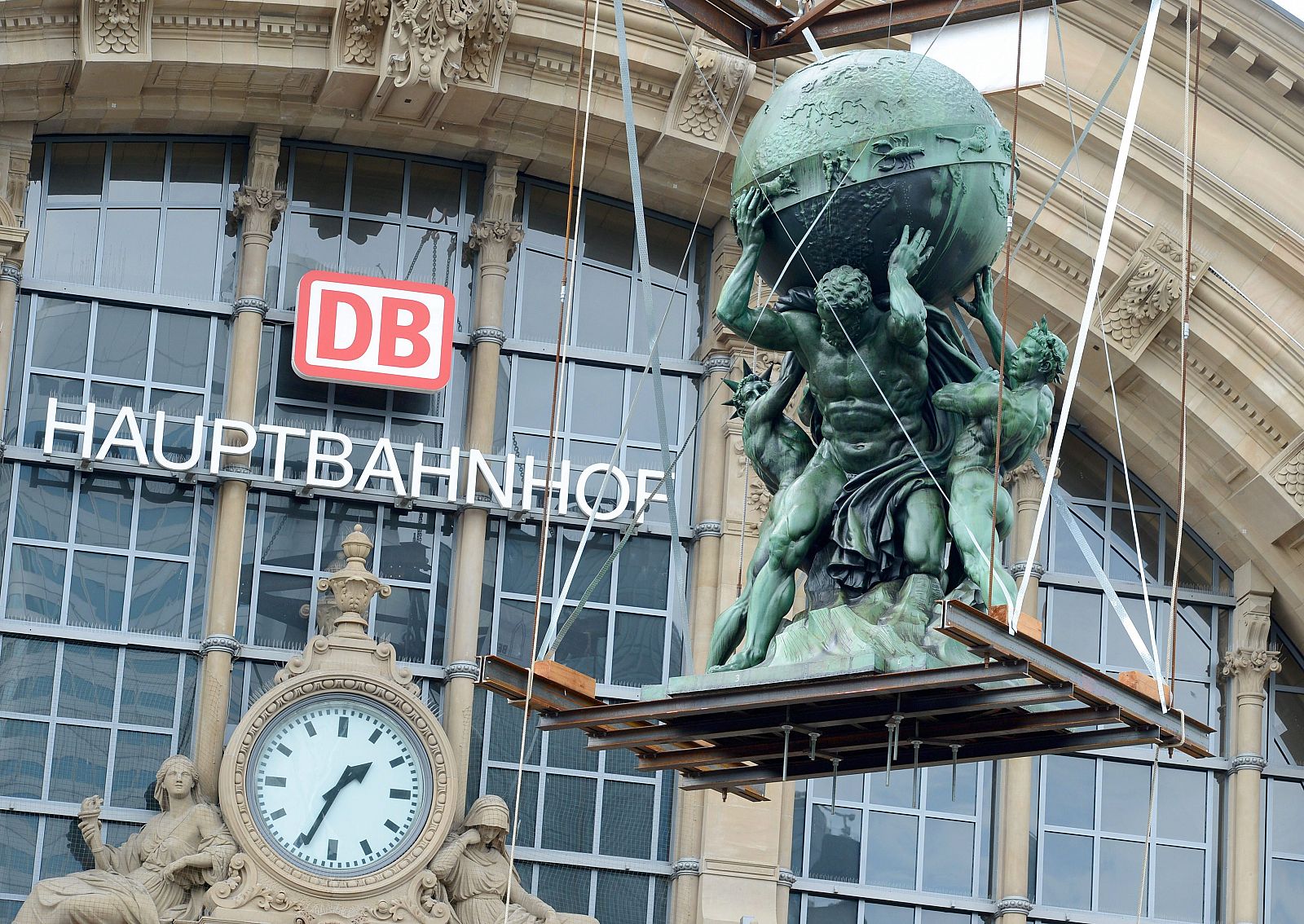 Una grúa coloca una escultura de Atlas en la estación de tren de Fráncfort