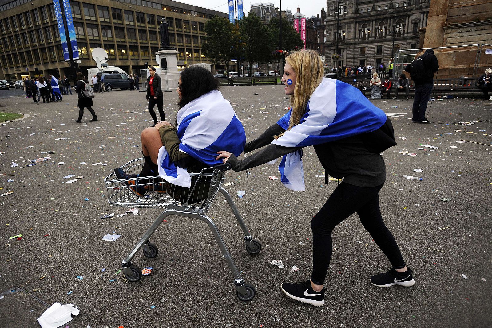 Una joven lleva a otra colega independentista en un carrito de la compra en Glasgow tras el anuncio de su derrota en el referéndum.