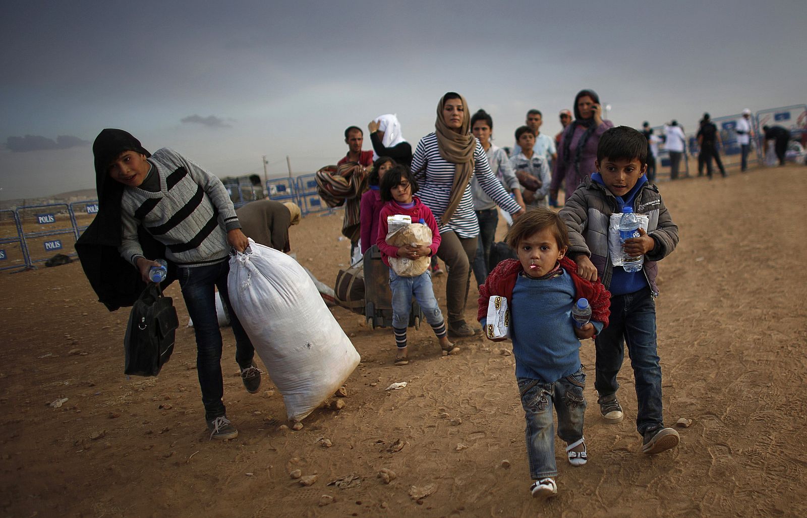 Kurdish Syrian refugees carry their belongings after crossing the Turkish-Syrian border near the southeastern town of Suruc in Sanliurfa province