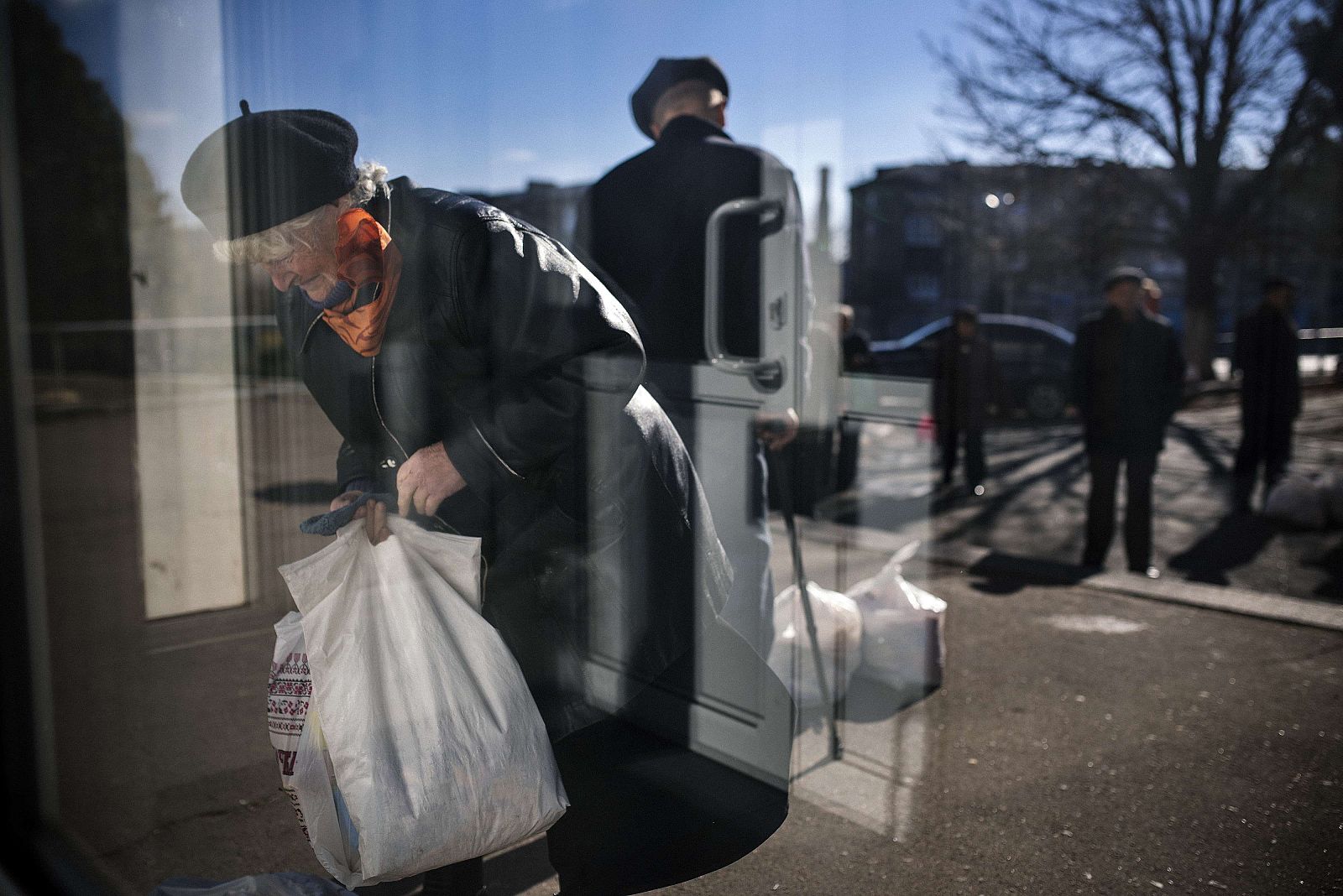 Una mujer ucraniana carga con un paquete de ayuda humanitaria en Donetsk, donde las bajas temperaturas ya han obligado los ciudadanos a encender la calefacción.