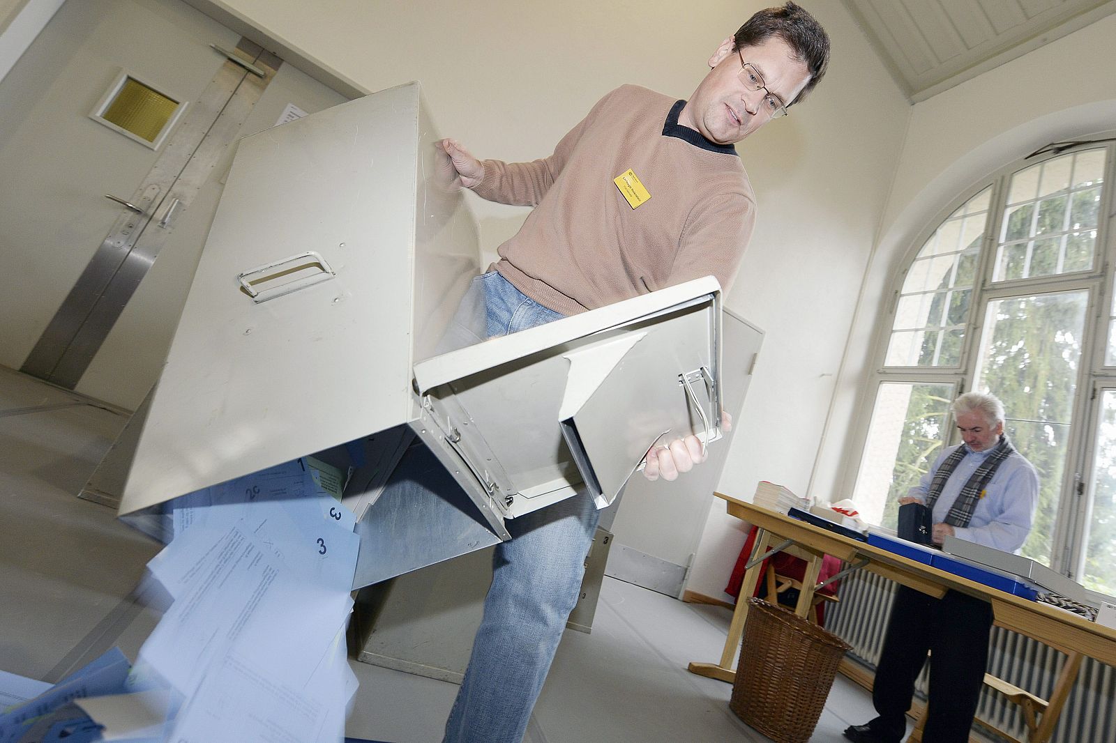 Un hombre vacía una urna en un centro de votación en Zurich, Suiza.