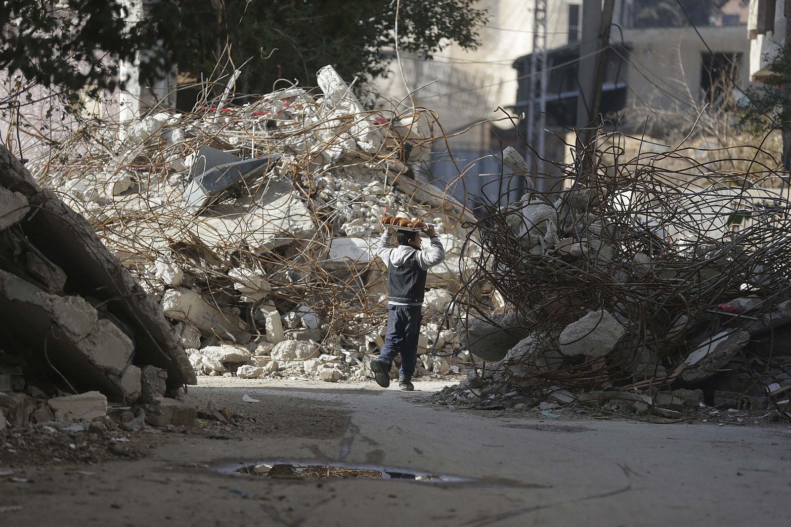 Un niño que vende golosinas camina entre las ruinas en Duma, cerca de Damasco.