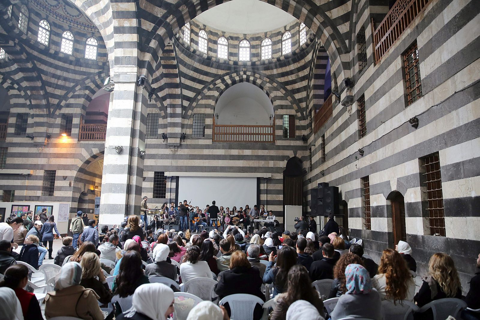 Ciudadanos sirios aisten a un concierto en Damasco una actividad promovida por la ONU en favor de los damnificados por la guerra en Siria.