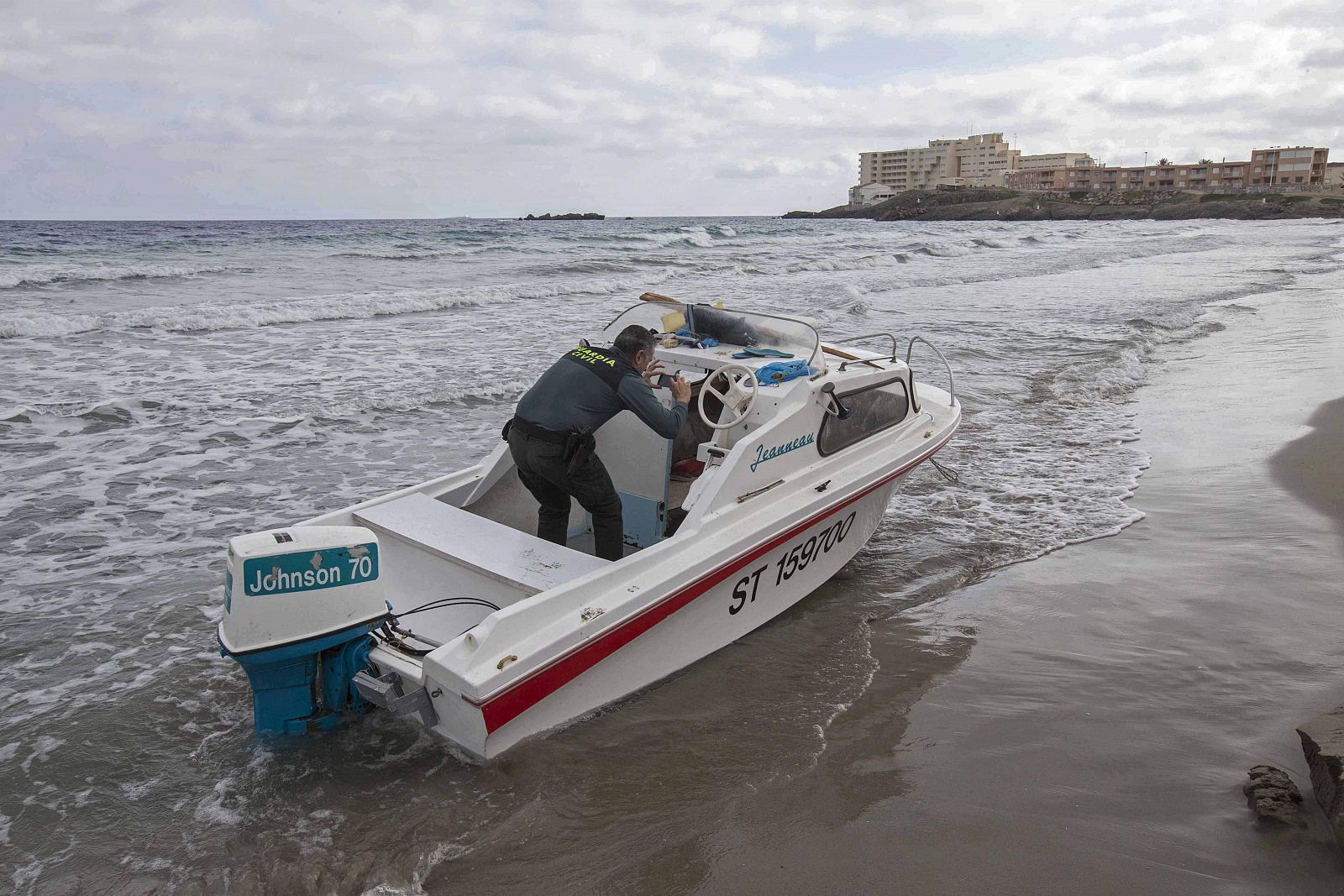 Un agente de la Guardia Civil fotografía el interior de la embarcación en la que once inmigrantes, seis de ellos menores de edad, han llegado a una playa de La Manga