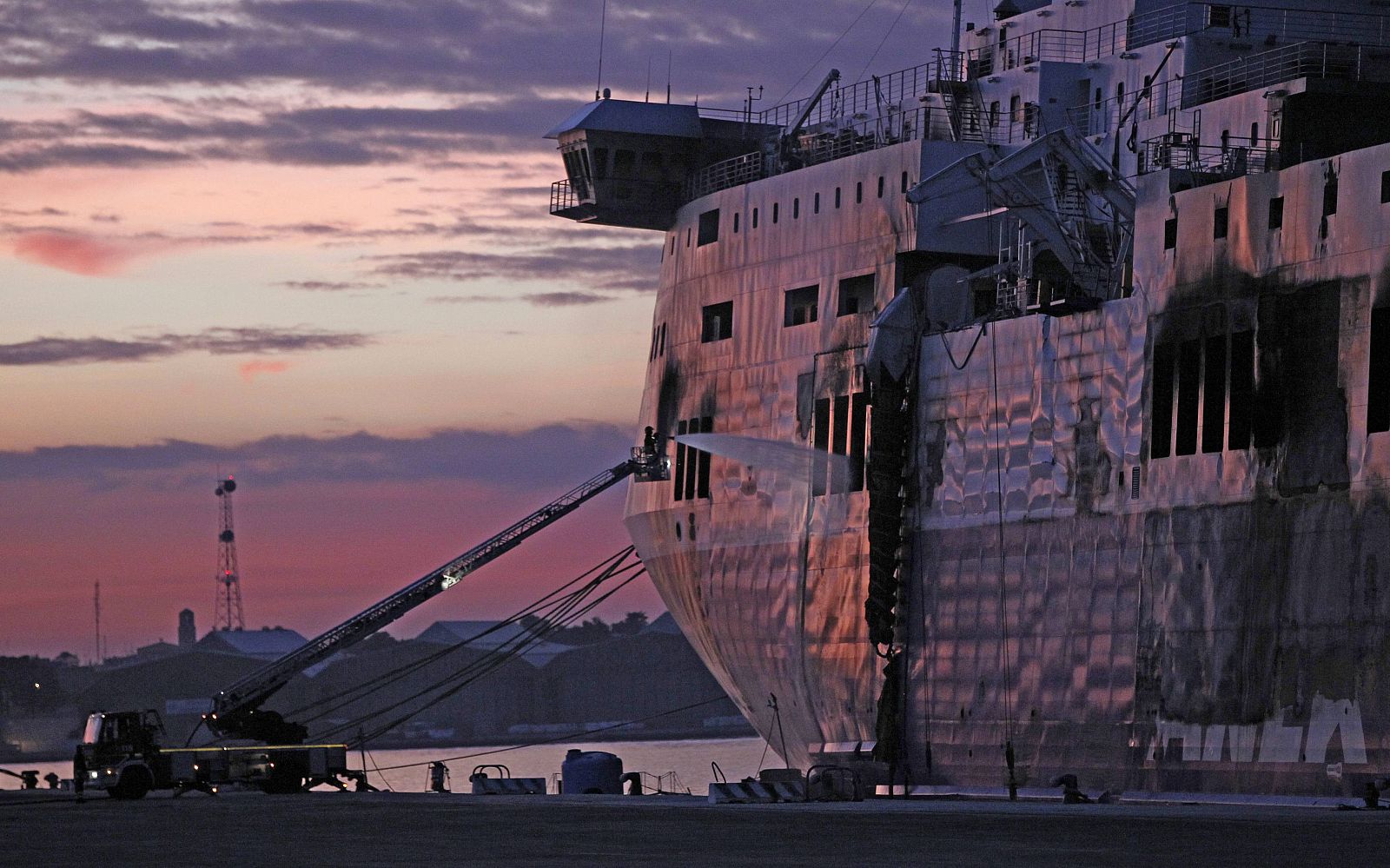 Un bombero apaga los focos aún sin extinguir del ferri 'Norman Atlantic', en el puerto italiano de Bríndisi.