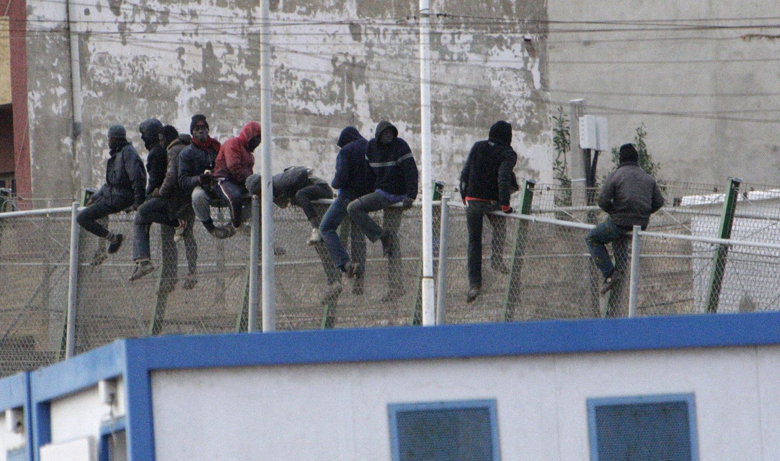 Una decena de personas inmigrantes encaramadas en la valla de Melilla en uno de los varios intentos de salto masivo de este martes.