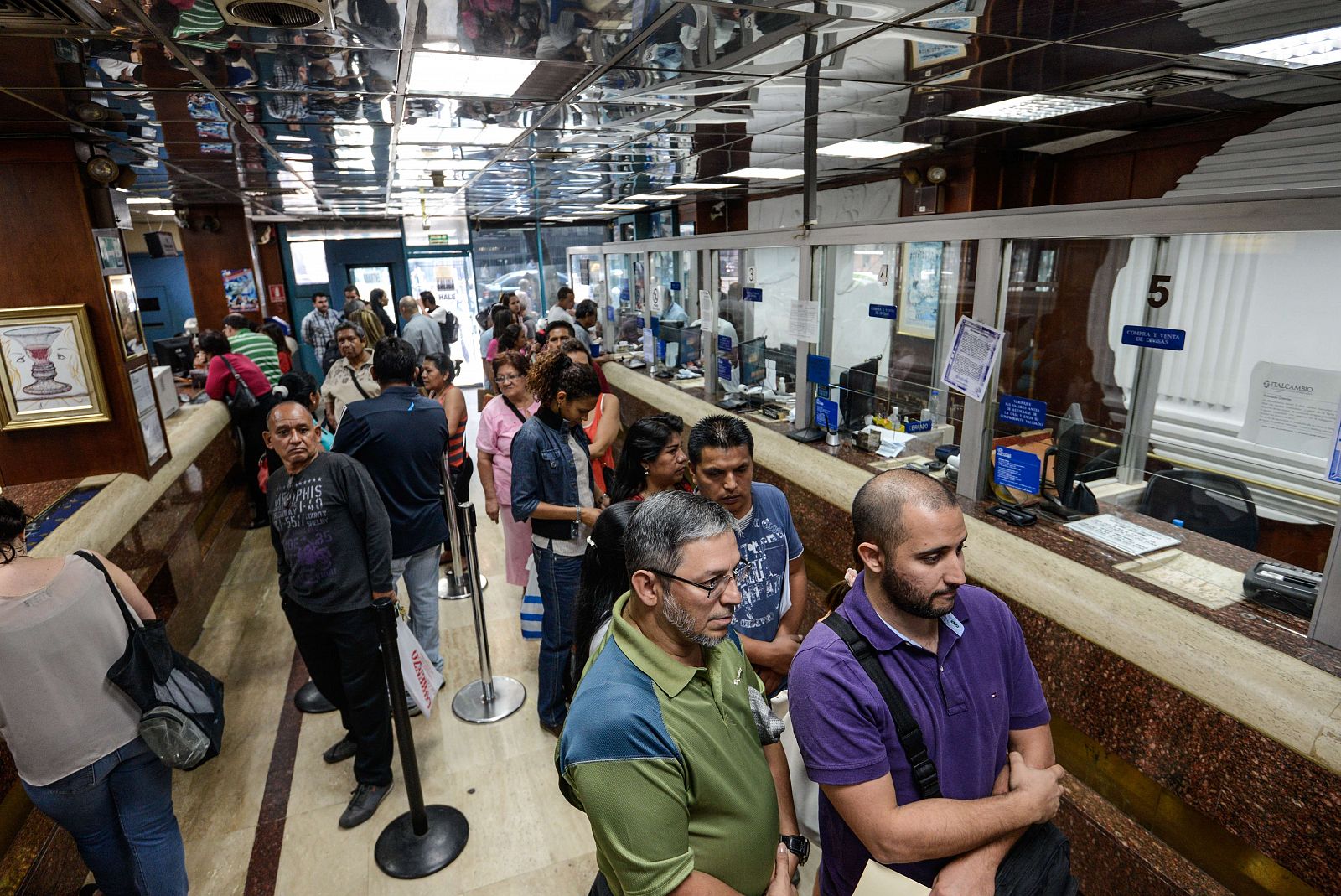 Varias personas hacen cola en una casa de cambio de Caracas el día de la reapertura del mercado cambiario después de 12 años de bloqueo gubernamental.