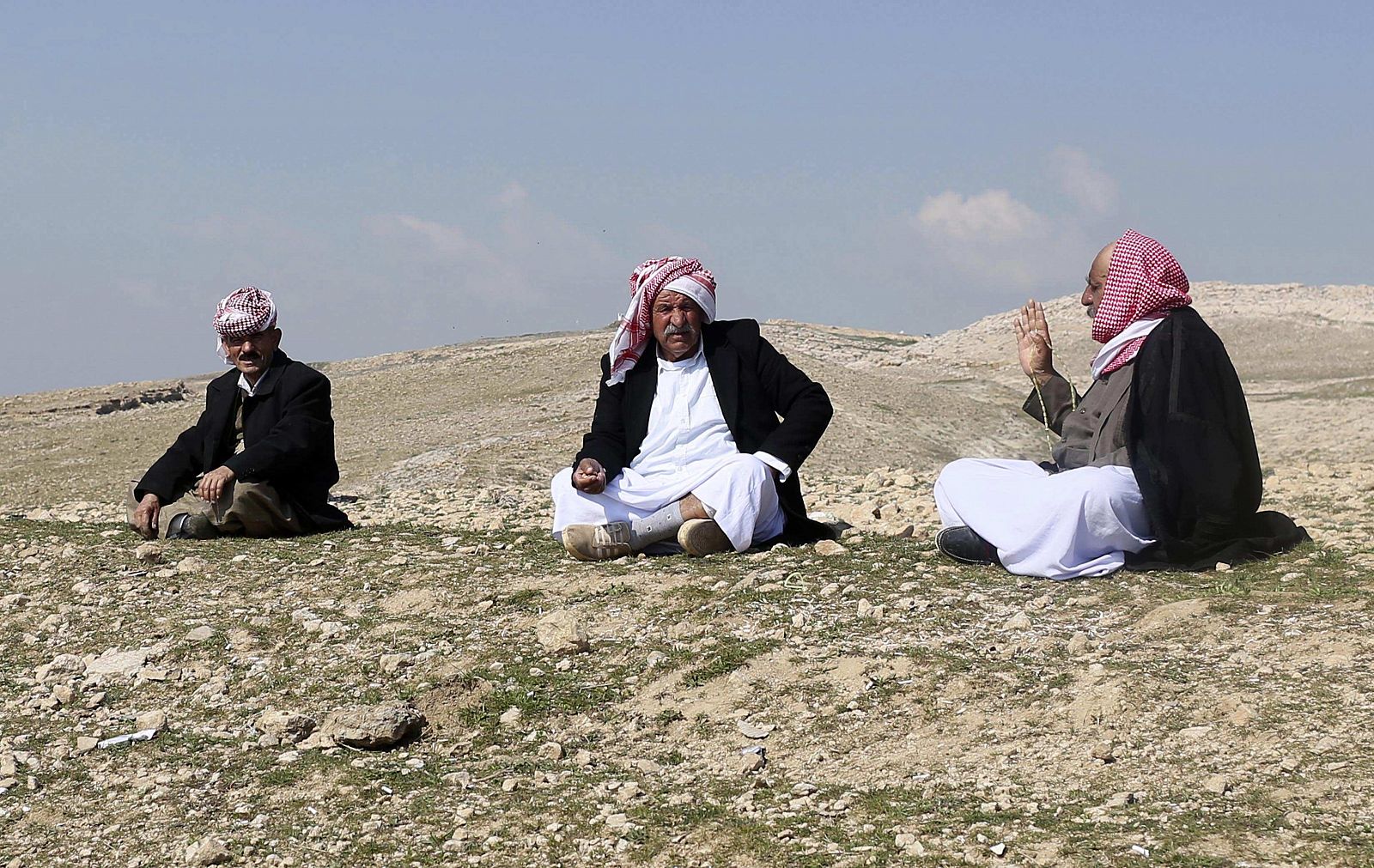 Yazidi refugees talk on a hill overlooking their refugee camp on the outskirts of Duhok