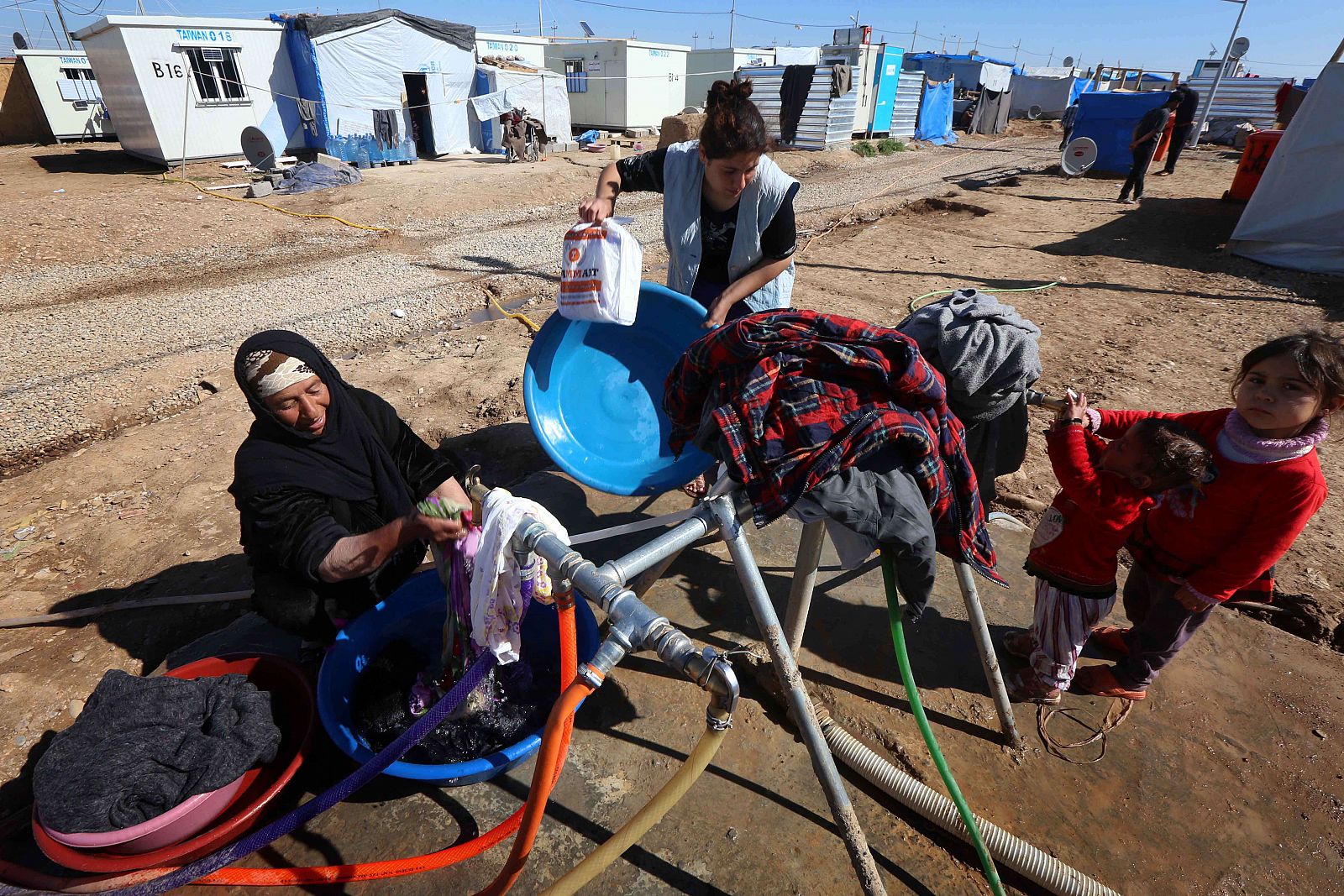 Desplazados iraquíes, que huyeron de sus hogares debido a los ataques de los yihadistas del Estado Islámico, lavan su ropa en el campamento de refugiados Harsham