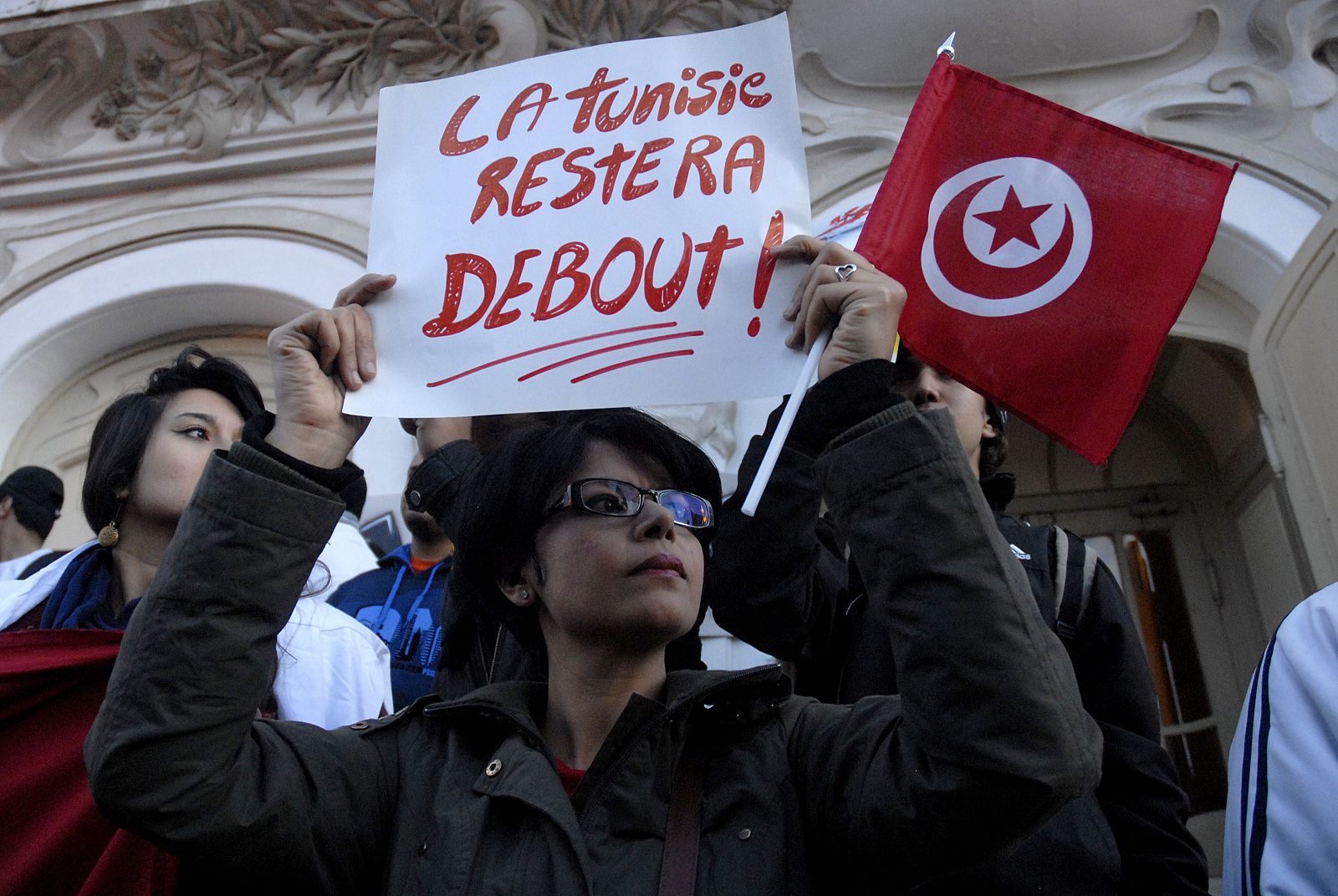 Una mujer sostiene un cartel con la frase en francés "Túnez seguirá en pie" en una protesta contra el atentado del Museo del Bardo