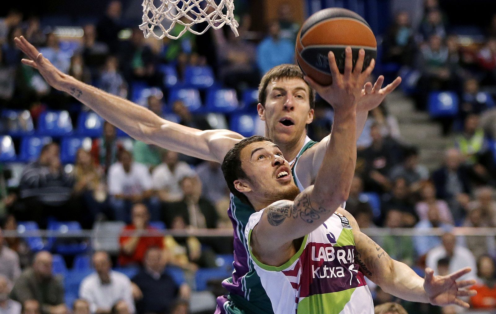 El base estadounidense del Laboral Kutxa Mike James entra a canasta ante el pívot del Unicaja Fran Vazquez.