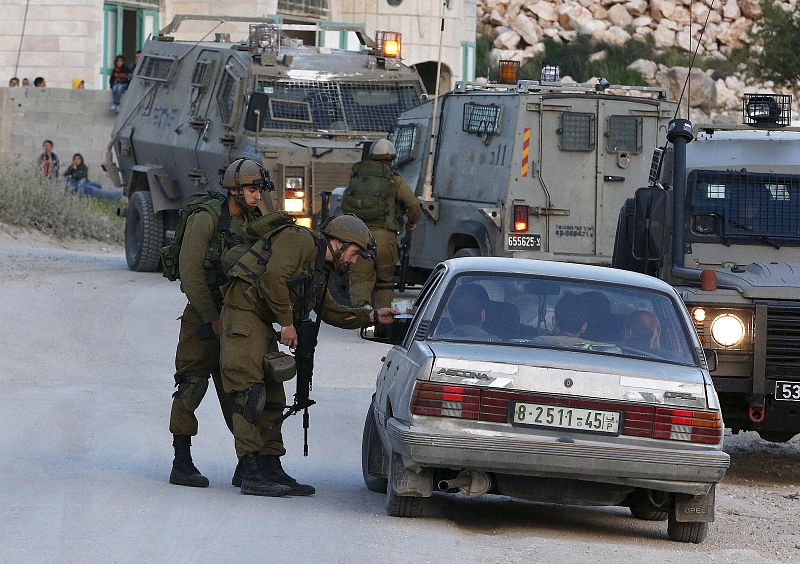 Israeli soldiers stop a car as they search for a missing Israeli near the West Bank city of Hebron
