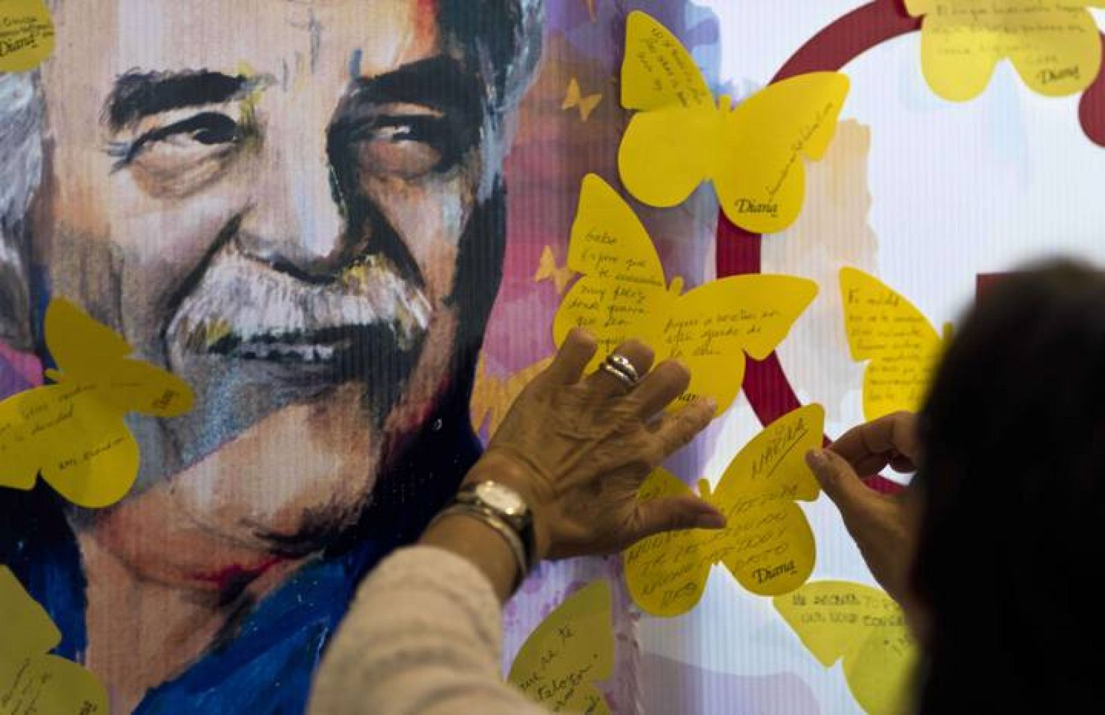 Una mujer pega una mariposa de papel amarillo con sus recuerdos sobre Gabriel García Márquez en una librería de Ciudad de México.