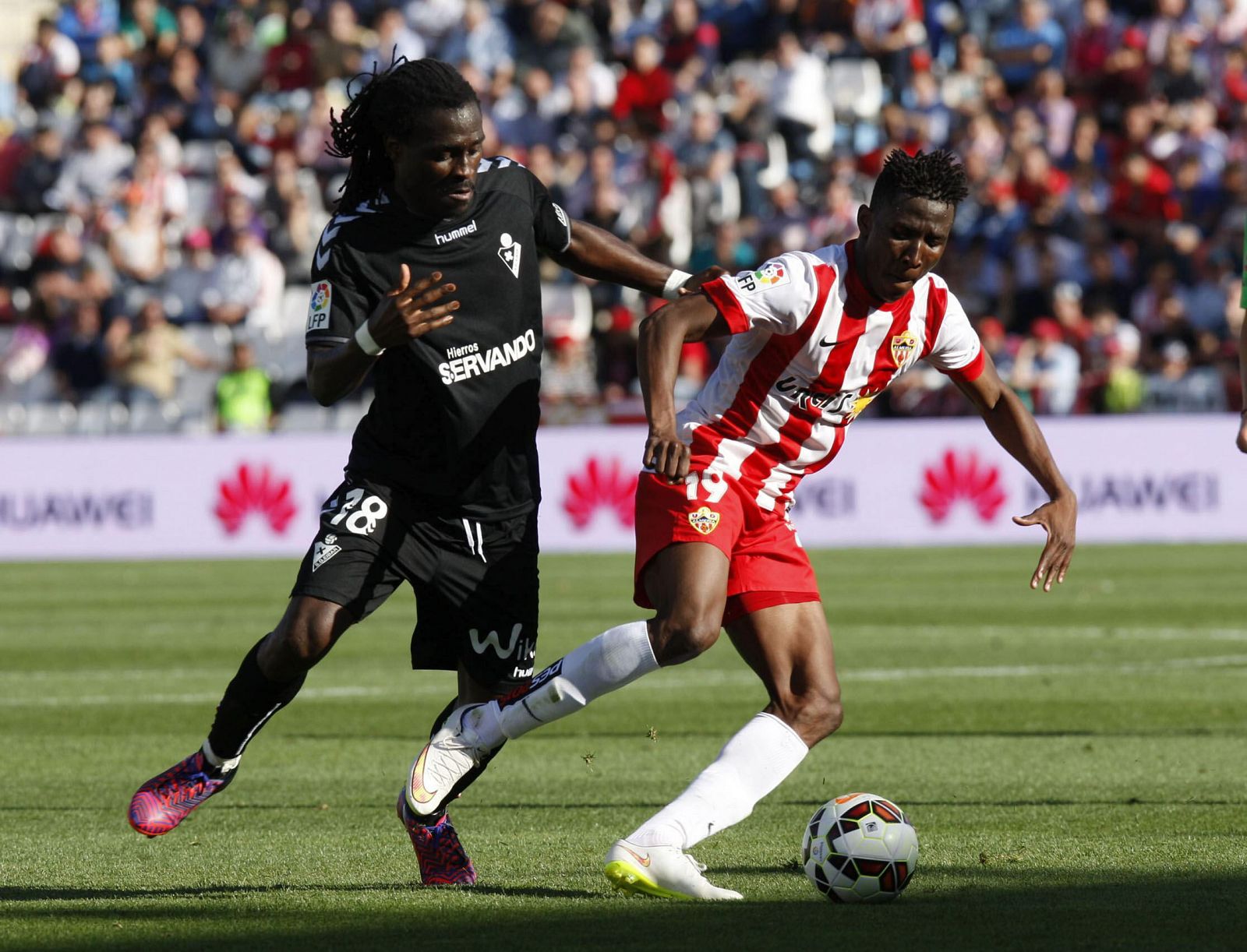 El delantero del Almería Jonathan Sundy Zongo con el balón seguido por el centrocampista del Eibar Derek Owusu Boateng.