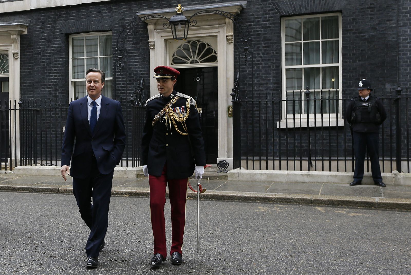 El primer ministro británico, David Cameron, abandona el número 10 de Downing Street acompañado de un soldado