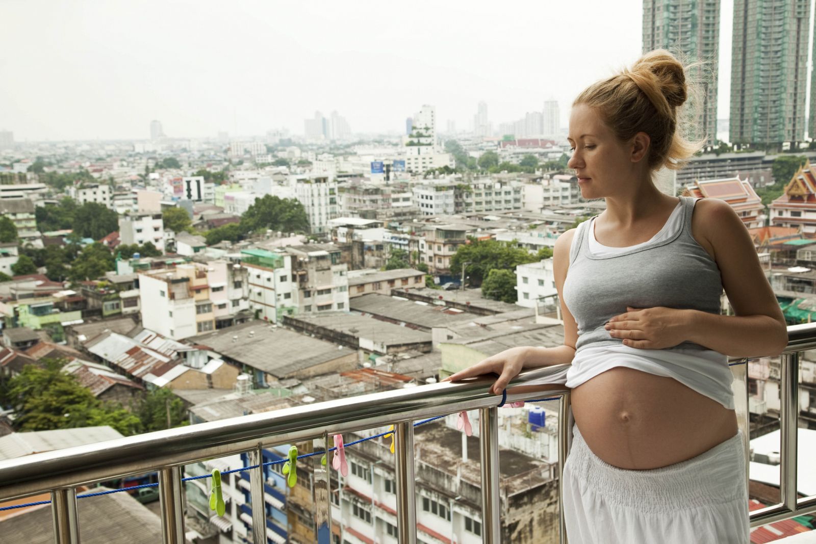 Una mujer embarazada observando el paisaje urbano.