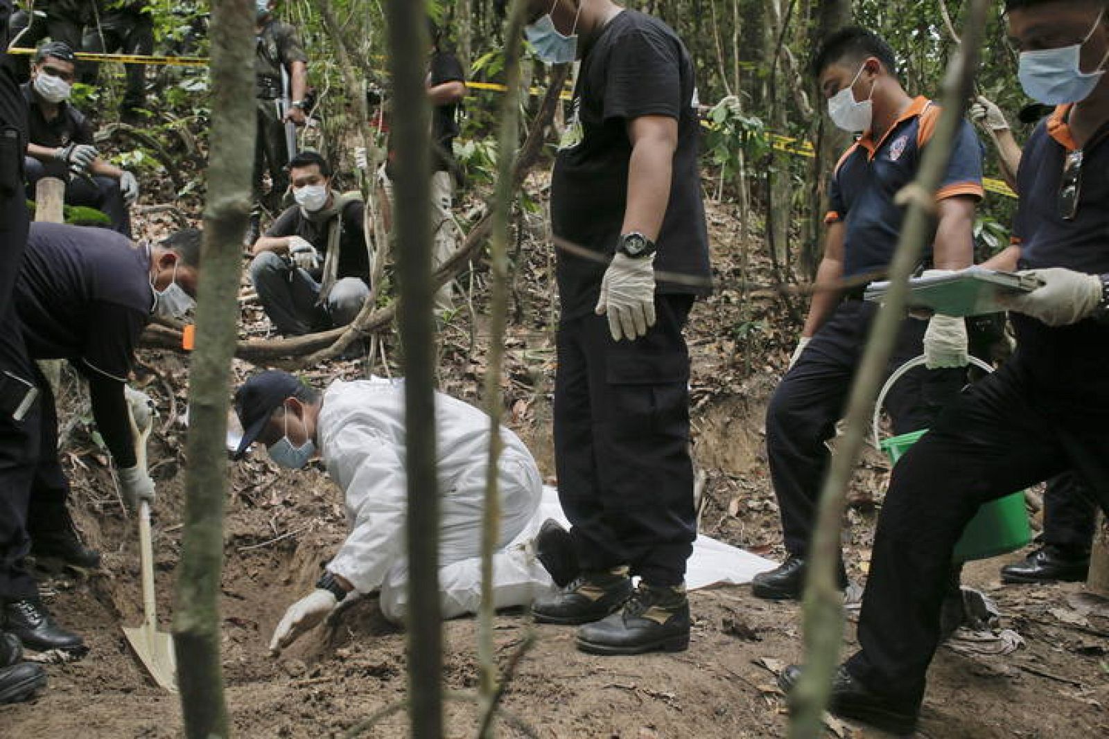 Un equipo de la policía forense malasia excava una fosa descubierta en las colinas Wang Burma en Wang Kelian, Perlis (Malasia)