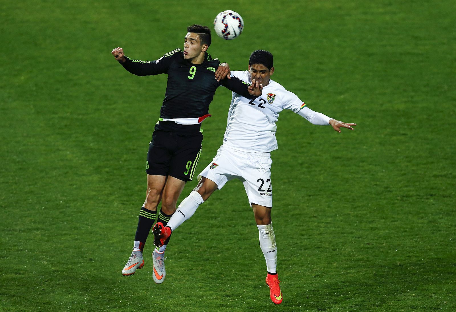 El delantero mexicano Raúl Jiménez (i) lucha un balón aéreo con el defensa boliviano Edward Mauro Zenteno (d).