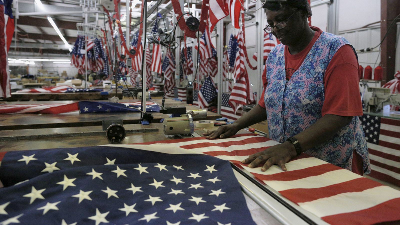 Una operaria cose una bandera de Estados Unidos en una fábrica