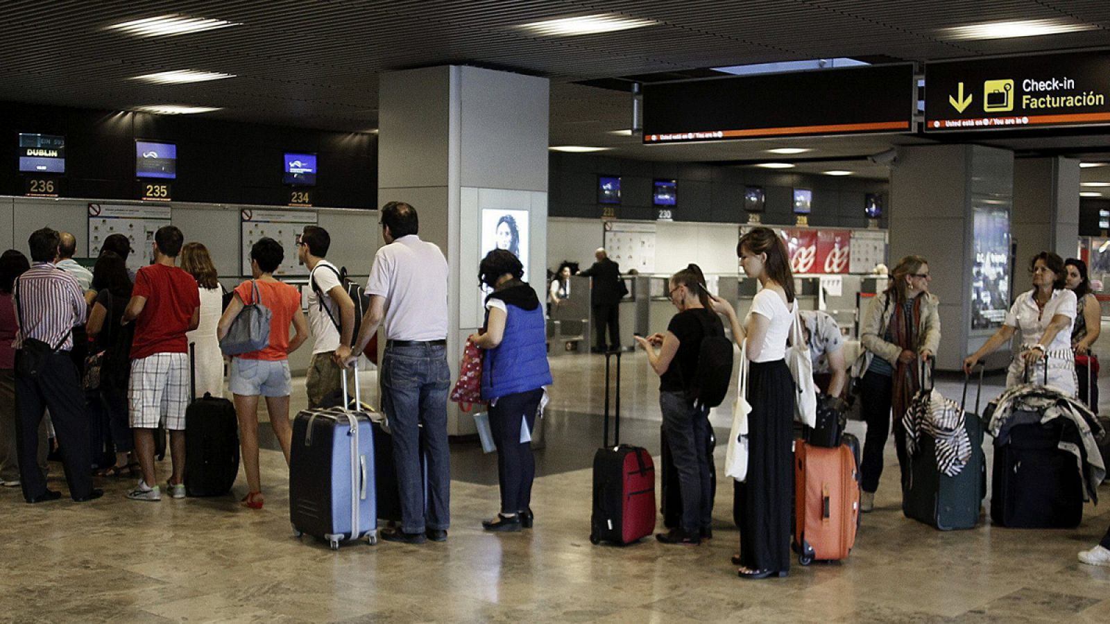 Un grupo de pasajeros hace cola ante un mostrador de facturación de Barajas