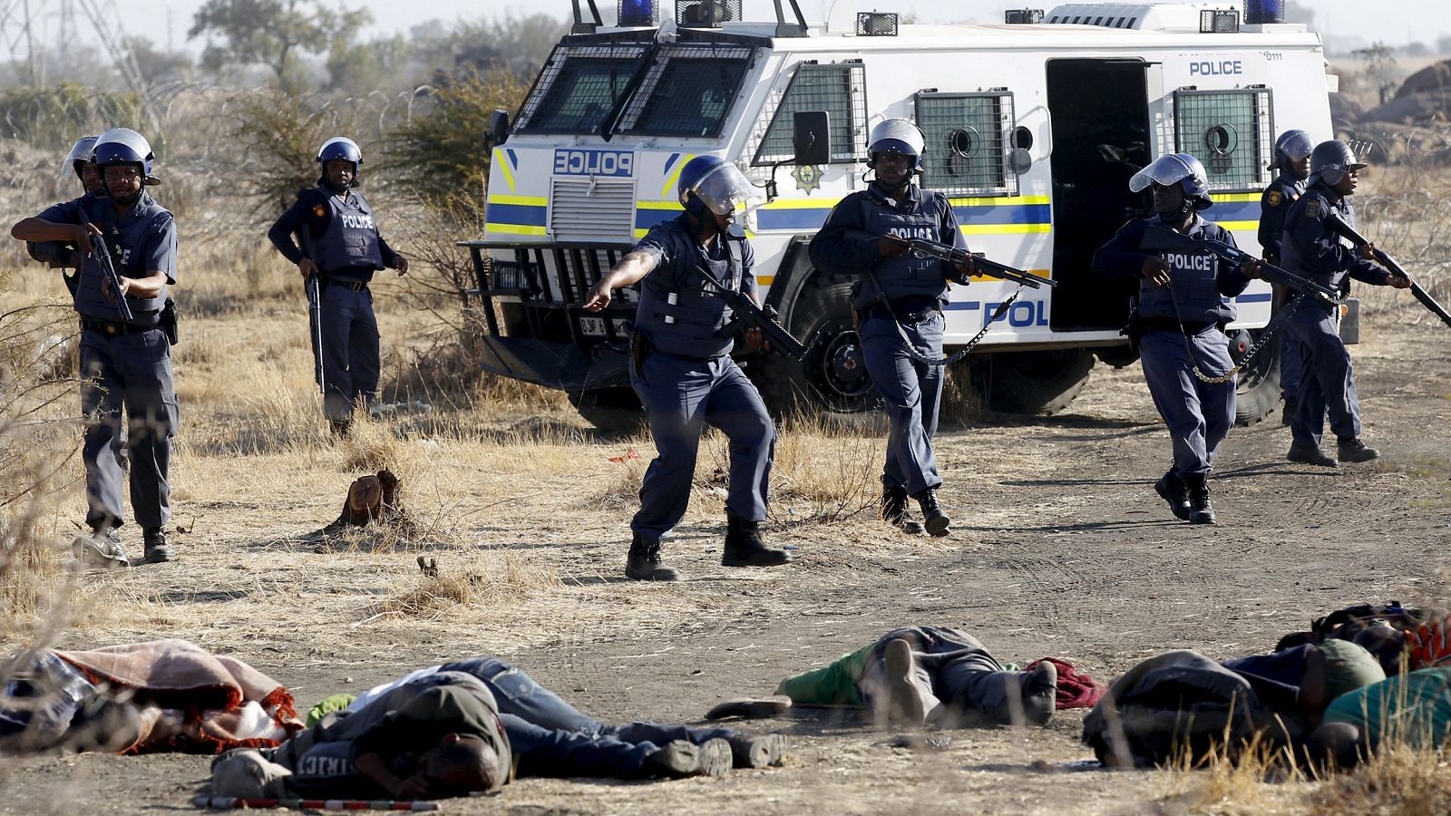 Policemen keep watch over striking miners after they were shot outside a South African mine in Rustenburg