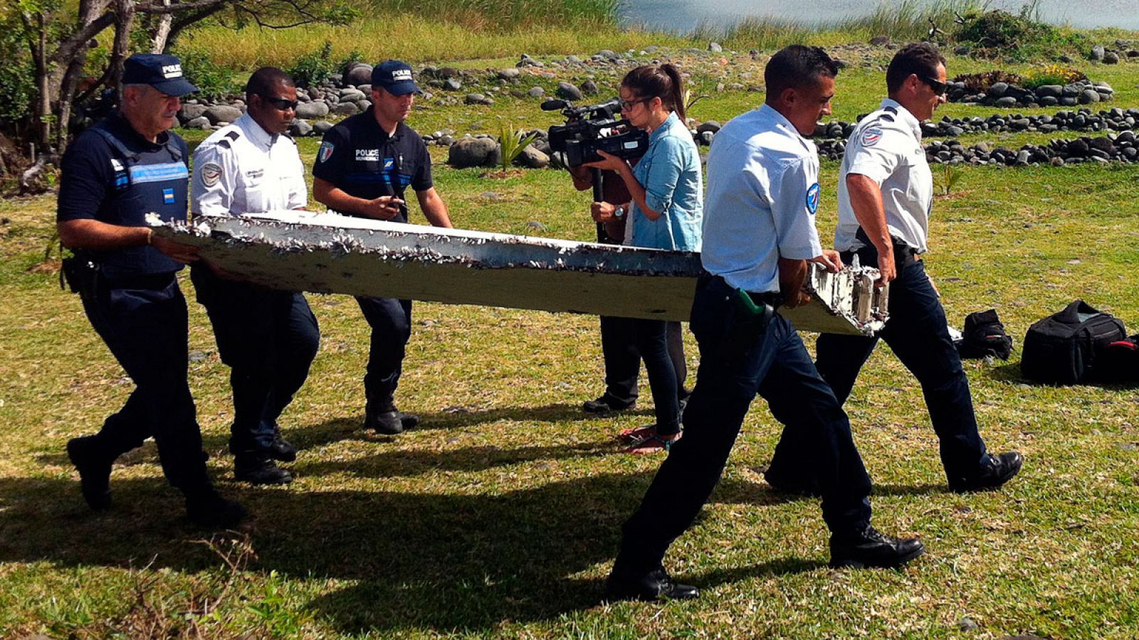 Funcionarios y miembros de la policía transportan los restos del ala de un avión encontrados en la isla de La Reunión, en el Océanos Índico