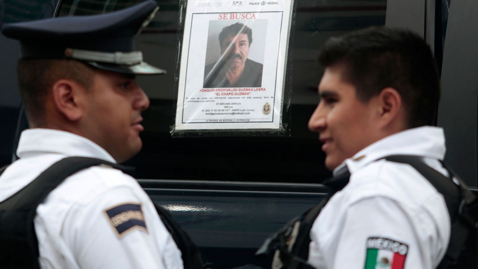 Dos policías federales ante a un coche patrulla con una foto de 'El Chapo' Guzmán en su ventana.