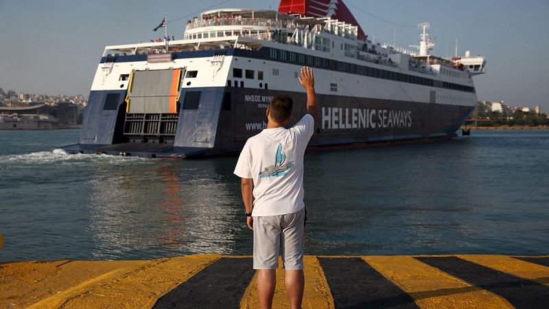 Un hombre despide a un barco que parte del puerto del Pireo