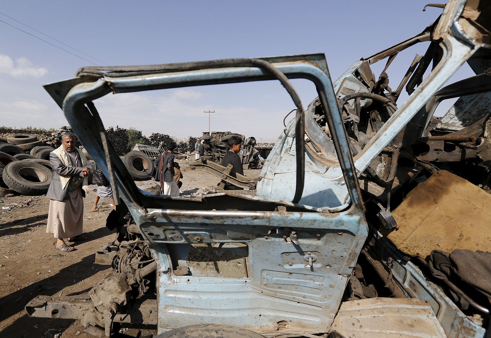Un hombre mira los restos de un coche calcinado en un atentado en la provincia noroccidental de Amran, en Yemen.