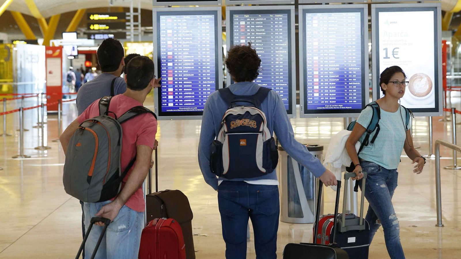 Varias personas observan una pantalla con la salida de vuelos de la Terminal 4 del aeropuerto Adolfo Suárez Madrid-Barajas