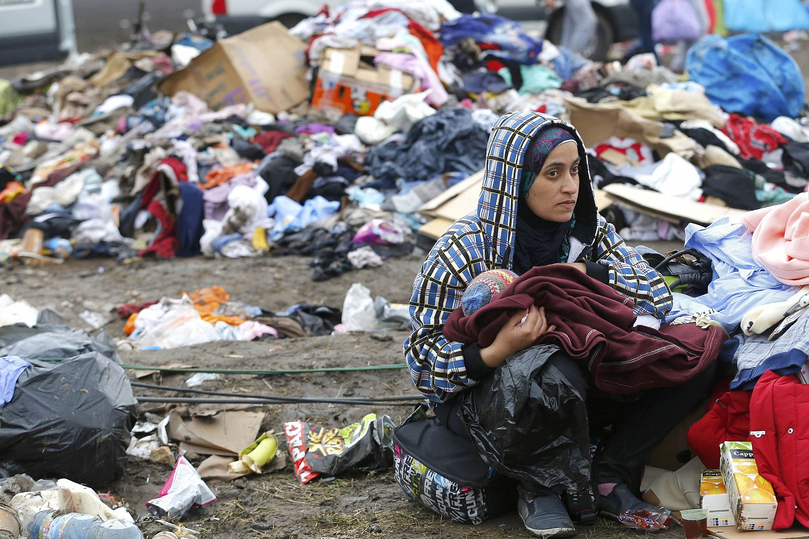 Una migrante da el pecho a su hijo rodeada de una pila de basura en un campo de refugiados en Roszke, Hungría