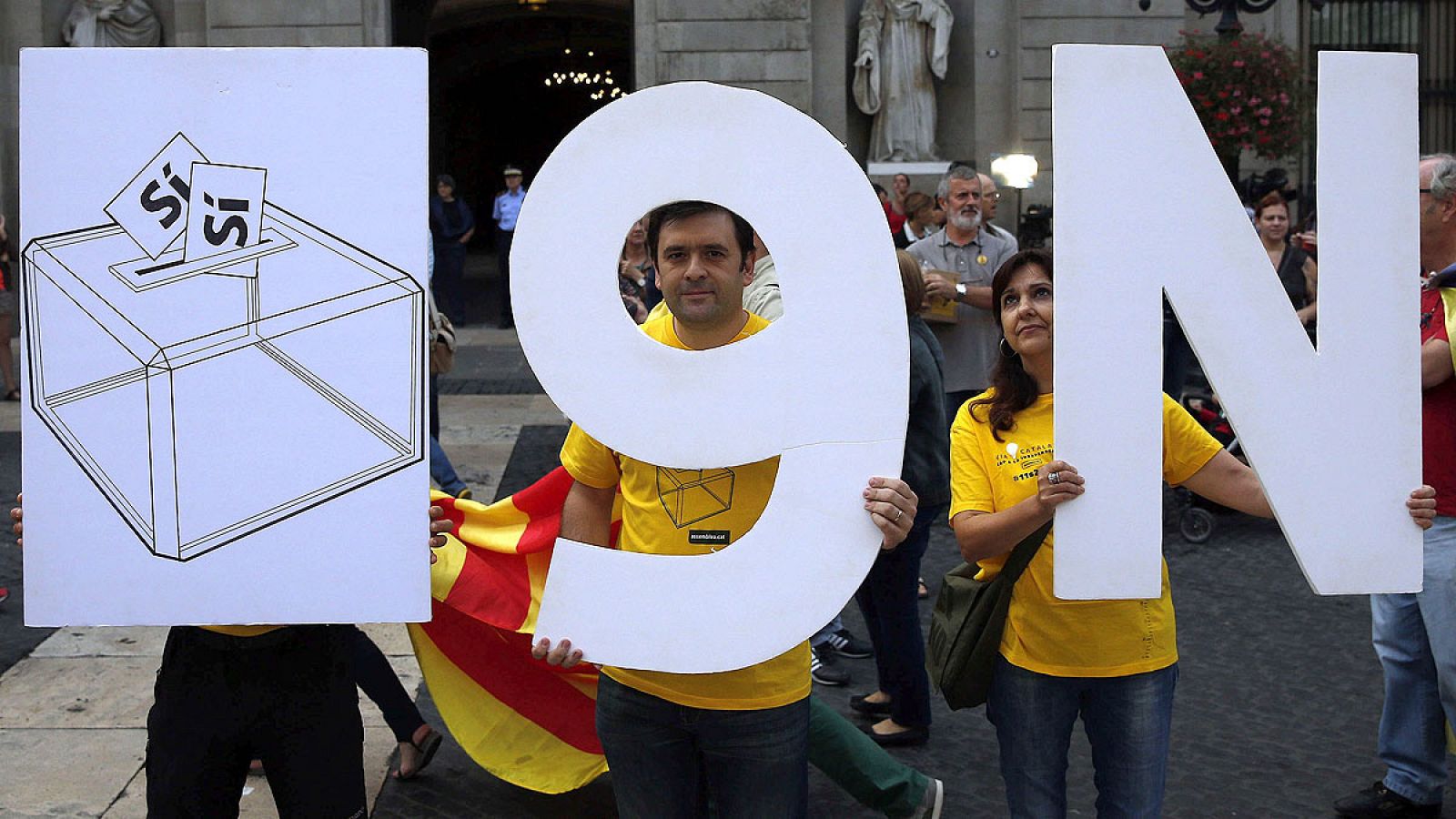 En la imagen, varias personas sostienen unos carteles sobre la consulta del 9N