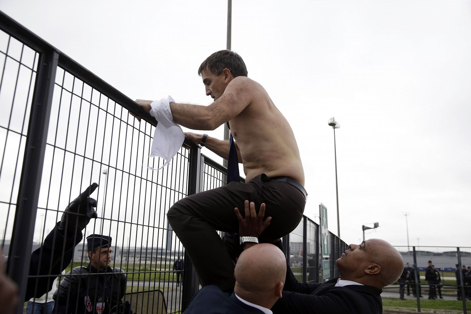 Varios agentes de seguridad ayudan al jefe de Recursos Humanos de Air France a saltar una valla en la sede de la aerolínea