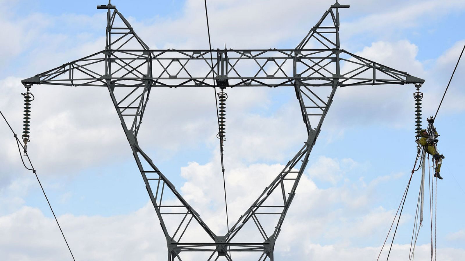 Un electricista trabaja en una torre de alta tensión