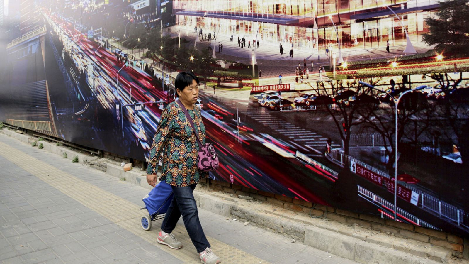 Una mujer pasa por delante del anuncio publicitario que cubre un edificio en construcción en el centro de Pekín