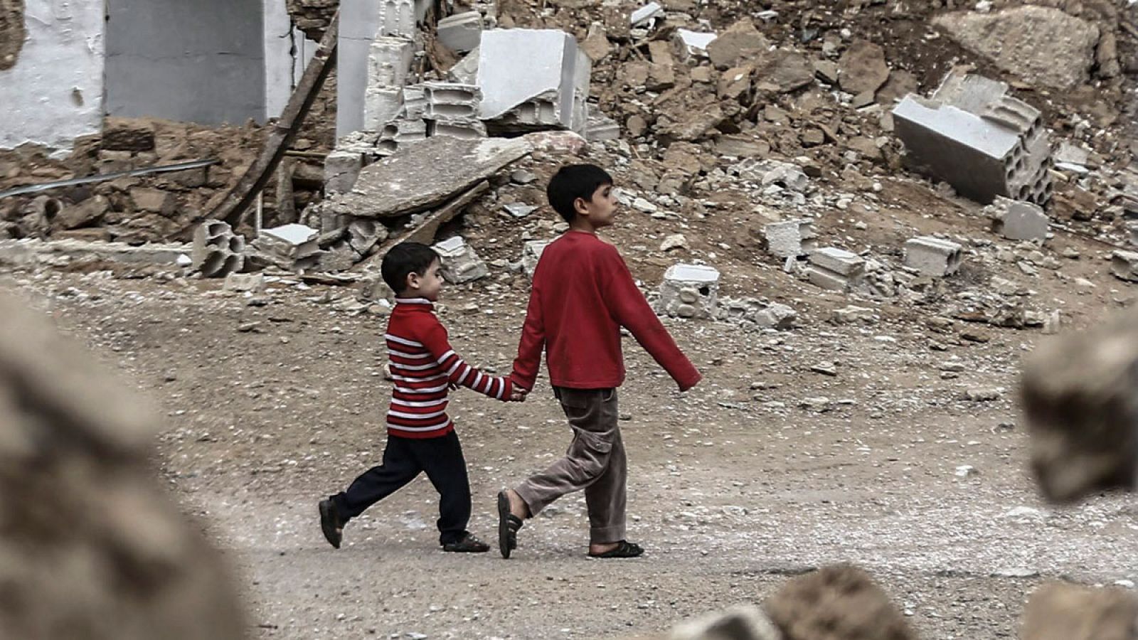 Dos niños sirios pasean entre las ruinas de una calle a las afueras de Damasco.