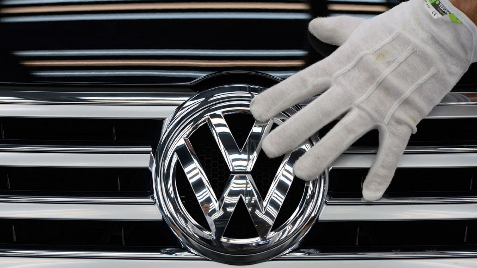 Un empleado de Volkswagen toca el logo de un vehículo del grupo en la fábrica transparente que la compañía tiene en la ciudad alemana de Dresde
