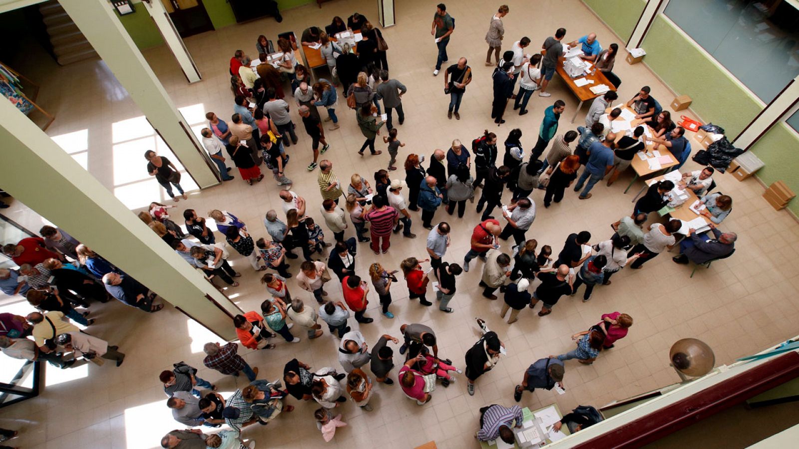 Varios ciudadanos hacen cola en un colegio electoral para votar.