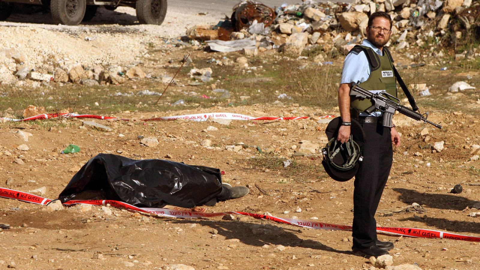 Un policía israelí aguarda junto al cuerpo de un palestino muerto tras intentar apuñalar a un soldado israelí, al norte de Hebrón