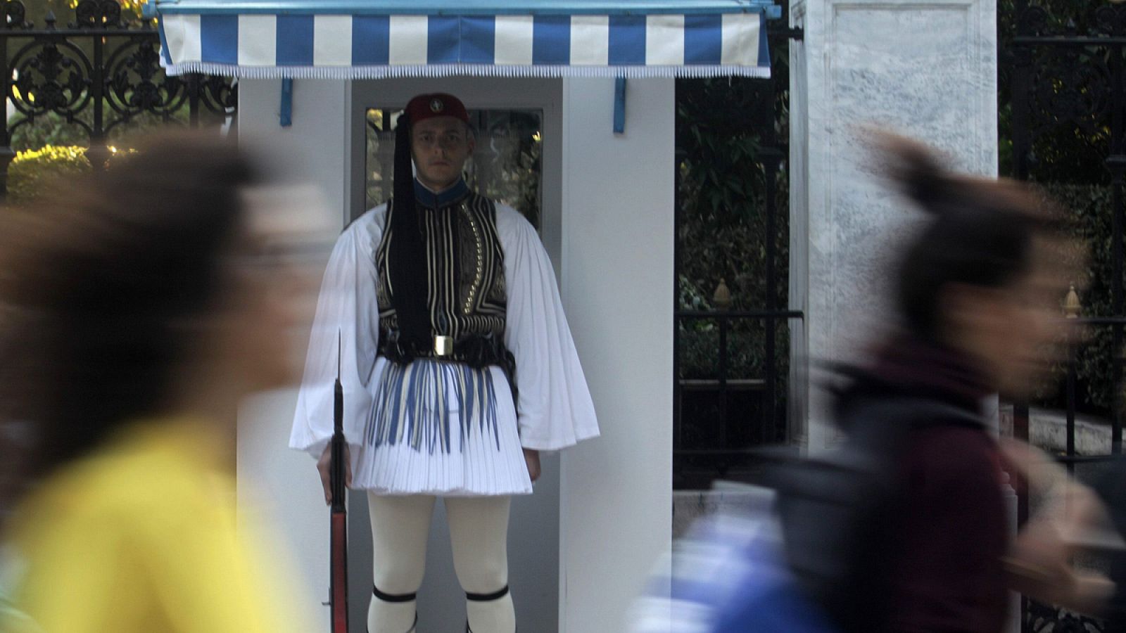 Dos mujeres pasan por delante de un guardia presidencial en Atenas